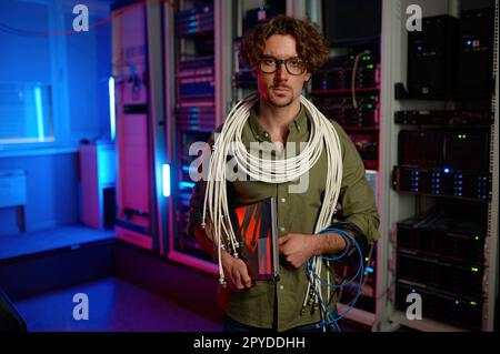 Portrait of signalman with many wires on shoulders and laptop in hand Stock Photo