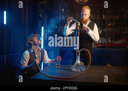 Portrait of retro guys smoking hookah pipe in bar Stock Photo