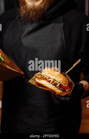 Man Black Gloves Holding Burger Hands Juicy Burger Close Appetizing burger. Stock Photo