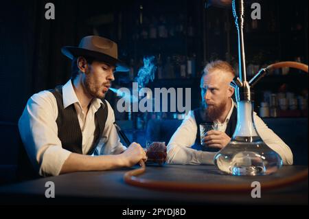 Stylish gangsters smoking hookah in bar having business meeting Stock Photo