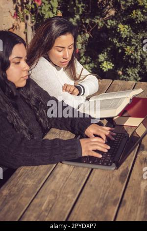 young mother helps daughter do college work, in home garden Stock Photo