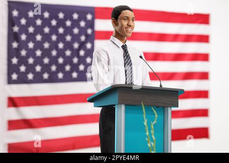 Young african american man on a pedestal giving a speech in front of a USA flag Stock Photo