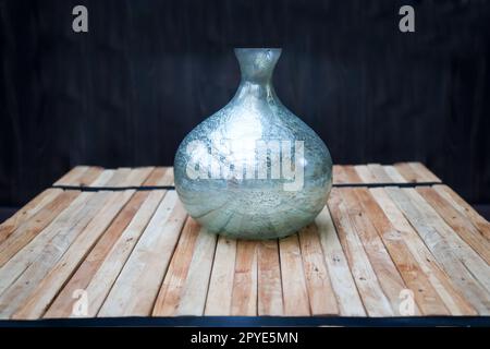 A still life with a blue vase on a stack of wooden slats, against a dark background. Stock Photo