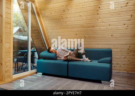 Middle aged man has retired to a country house and is reading a book lying on the sofa Stock Photo