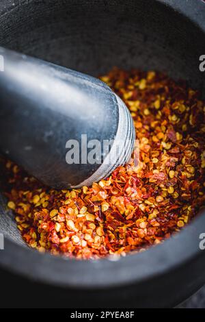 Dry chili pepper flakes. Crushed red peppers in mortar. Stock Photo