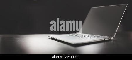 Grey laptop on the dark table on the black background. Stock Photo