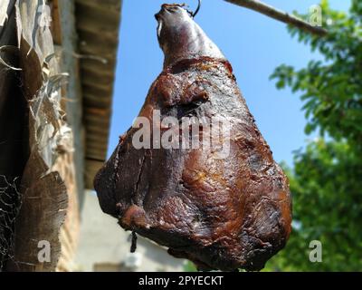 Homemade ham. Farm product of Serbian producers. Dried salted smoky pork hind leg. Meat delicacy. Meat suspended in the air to dry. Protein diet. Traditional cooking Stock Photo