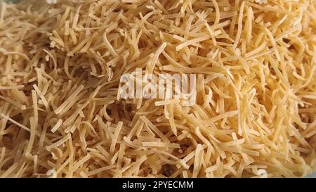 Thin dry vermicelli. Wheat flour product containing gluten, vitamins, carbohydrates, proteins and fats. Small pasta close-up. Fast food. Stock Photo