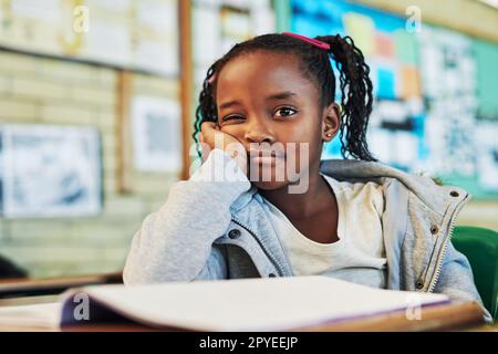 Shes waiting on everyone else to finish writing the test. Portrait of an elementary school girl working in class. Stock Photo