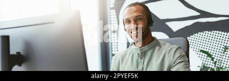 Smiling african businessman working on computer and making notes while sitting in modern office Stock Photo