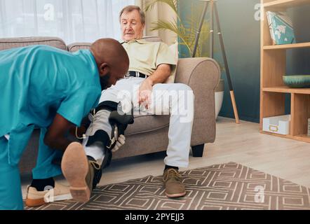 Senior man, physiotherapist and leg brace for rehabilitation, injury and support for wellness, muscle or knee. Man, sofa and physiotherapy with nurse, doctor or caregiver for health, training or talk Stock Photo