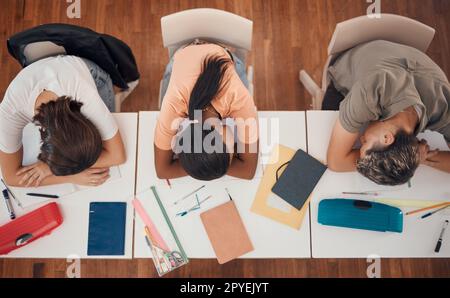 Sleeping, study and desk group students with learning, education and school fatigue, depression or mental health risk. Burnout, stress and tired friends with books on table in library or school above Stock Photo