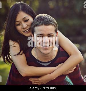 Loving and playing the day away. a happy young couple enjoying a piggyback ride outdoors. Stock Photo