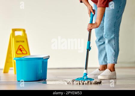 Cleaning, sign and woman mopping floor in office for hygiene, health and wellness. Spring cleaning, service and janitor, cleaner and female with mop, water bucket and caution wet floor warning notice Stock Photo