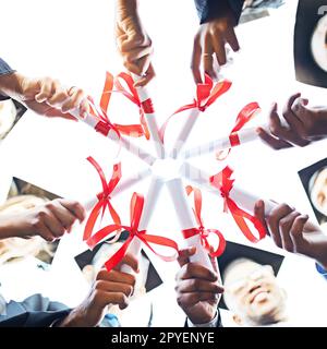 Its our weapon to change the future. Closeup shot of a group of university students holding their diplomas together on graduation day. Stock Photo