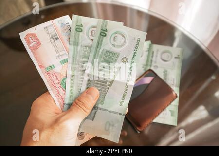 Dirham cash banknotes in hand with wallet. Financial education and Aed currency rate Stock Photo