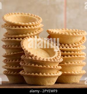 Stack of empty baked round canape baskets on a wooden board, round empty tartlets Stock Photo