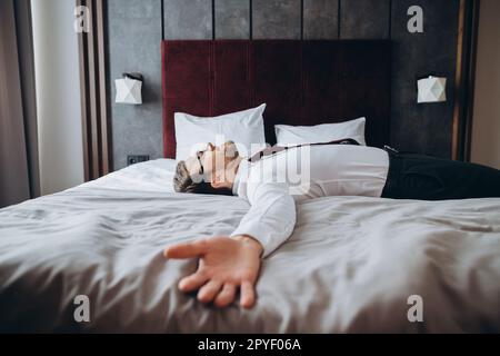 Exhausted businessman resting on bed after long air flight, jet lag. Stock Photo