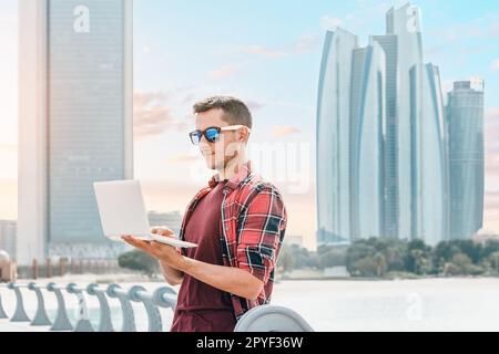 In a city that values progress and growth, a young man immerses himself in his work or studies amidst the towering skyscrapers of downtown Abu Dhabi Stock Photo