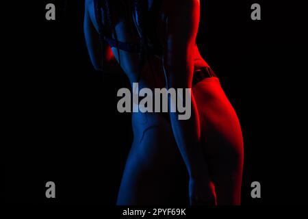 Slim body type. Young woman in underwear is in the studio with neon lights  Stock Photo by mstandret