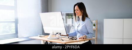 Woman Using Adjustable Height Standing Desk In Office Stock Photo