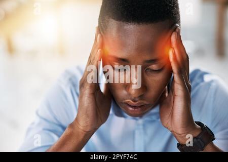 Hopefully this headache will go away soon. a young and stressed businessman suffering from a headache while trying to work in the office. Stock Photo