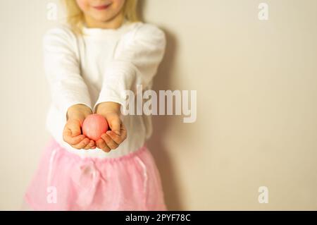 Children hands holding one pink Easter egg. Happy Easter. Preparation for Easter and spring. Stock Photo