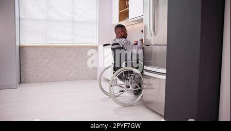 Young Disabled Man Sitting On Wheel Chair Preparing Food Stock Photo