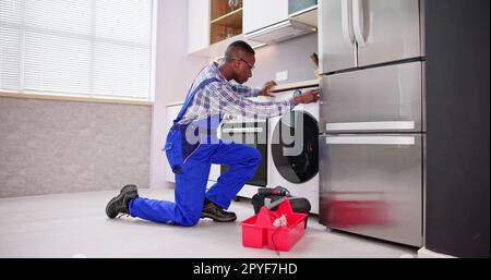 Young Man In Overall Repairing Washing Stock Photo