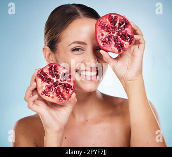 Face portrait, skincare and woman with pomegranate in studio on a blue background. Organic cosmetics, beauty and female model with product, fruit or food for vitamin c, nutrition and healthy diet. Stock Photo