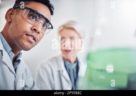 Face, doctors and beaker in laboratory for research, testing and analysis. Science, innovation and teamwork of man, senior woman and researchers with goggles looking at glass flask for experiment. Stock Photo