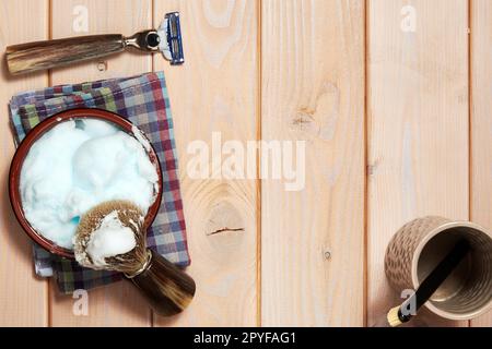 Classic shaving razor blade and brush and bowl with foam on the wooden table. Barbershop theme backgrounds. Copy space for text Stock Photo