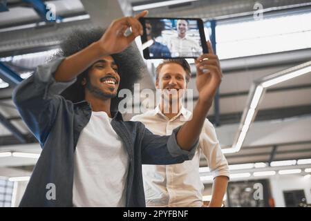 Lets take one for the website. two young businessmen taking a selfie with a tablet in their office. Stock Photo