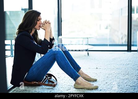 Shes cracking under the pressure. a stressed businesswoman sitting on the floor outside the boardroom. Stock Photo