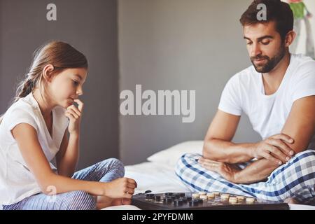 Thinking about her next move. a young father playing a board game with his adorable little daughter at home. Stock Photo