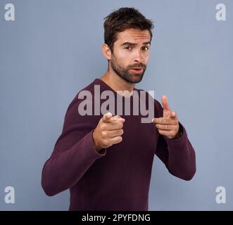 Whats cookin good lookin. Studio shot of a handsome young man with a cool attitude pointing against a gray background. Stock Photo