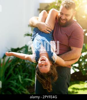 Boisterous play isnt just for boys. an adorable little girl having fun with her father in their backyard. Stock Photo