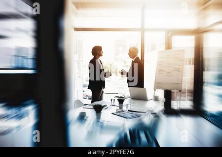 Getting down to serious office discussions. two business colleagues talking together in a boardroom. Stock Photo