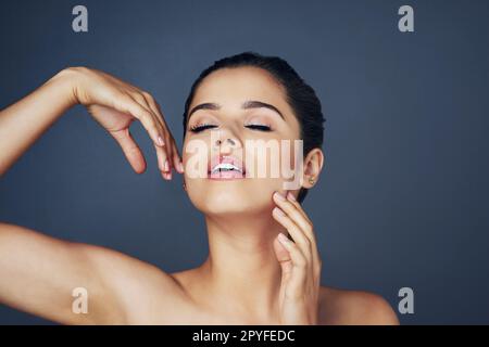 Soft to the touch. Studio shot of a beautiful young woman with flawless skin posing against a blue background. Stock Photo