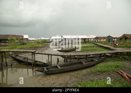 Ondo State, Nigeria - May 2nd, 2023 - A woman walking on the wooden bridge in a polluted environment of the Abereke Riverine area of Ilaje Community. Stock Photo
