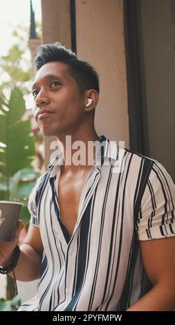 Young man sits outside and drinks coffee Stock Photo