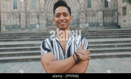 Young man tourist crosses his arms, looks at the camera and smiles Stock Photo