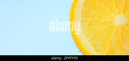 Lemon slice in water against light blue background with space for text, closeup Stock Photo