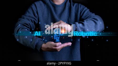 A person stretches out his hand with a model of a robot on his palm. It represents the use of AI and Robotic systems to research and work. Stock Photo