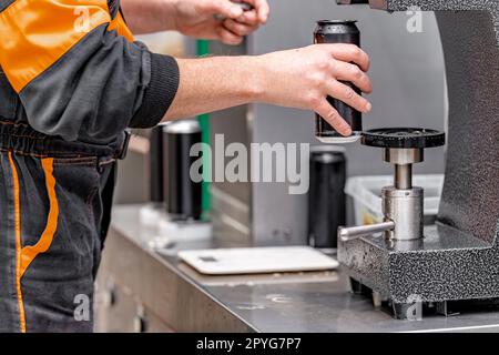 closed with the lid of beverage cans in an automatic capping machine in a brewery Stock Photo