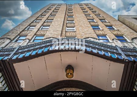 Art Deco sky scraper building with ornate curved canopy over entrance - perspective looking up Stock Photo