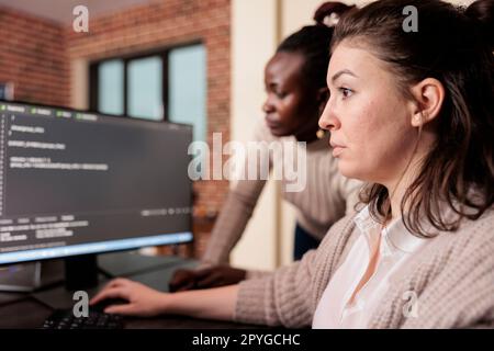 Tech enginners working on terminal window with html script, typing server code on computer, sitting at desk in big data room. Software developers programming user interface in it developing agency. Stock Photo
