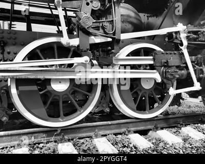 Retro train two wheels. Sleepers and rails, mechanisms, pistons and guides. Locomotive of the 19th early 20th century with a steam engine. Vintage style. Black - white photo. Beautiful card. Stock Photo