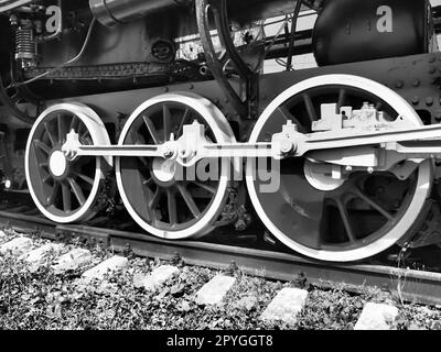 Retro train three wheels. Sleepers and rails, mechanisms, pistons and guides. Locomotive of the 19th early 20th century with a steam engine. Vintage style. Black - white photo. Beautiful card. Stock Photo