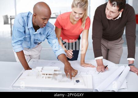 I suggest we change the layout over there...Three architects discussing their architectural model. Stock Photo